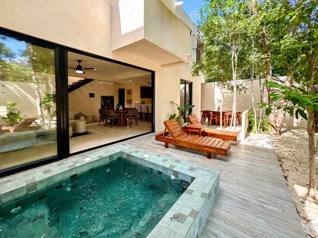 A modern house in Casa Organica, Tulum, with a private hot tub and outdoor lounging area surrounded by trees, blending indoor and outdoor living in Region 15.