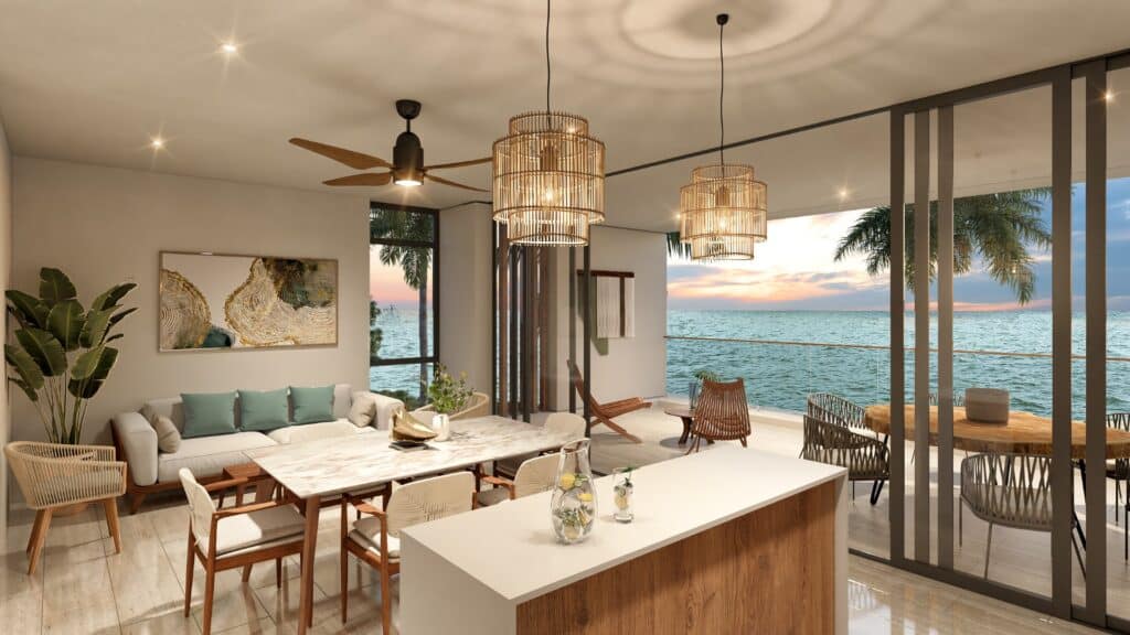 Living room in Duna Residences with large windows showing the ocean and sunset, modern decor, a ceiling fan, and elegant lighting fixtures.