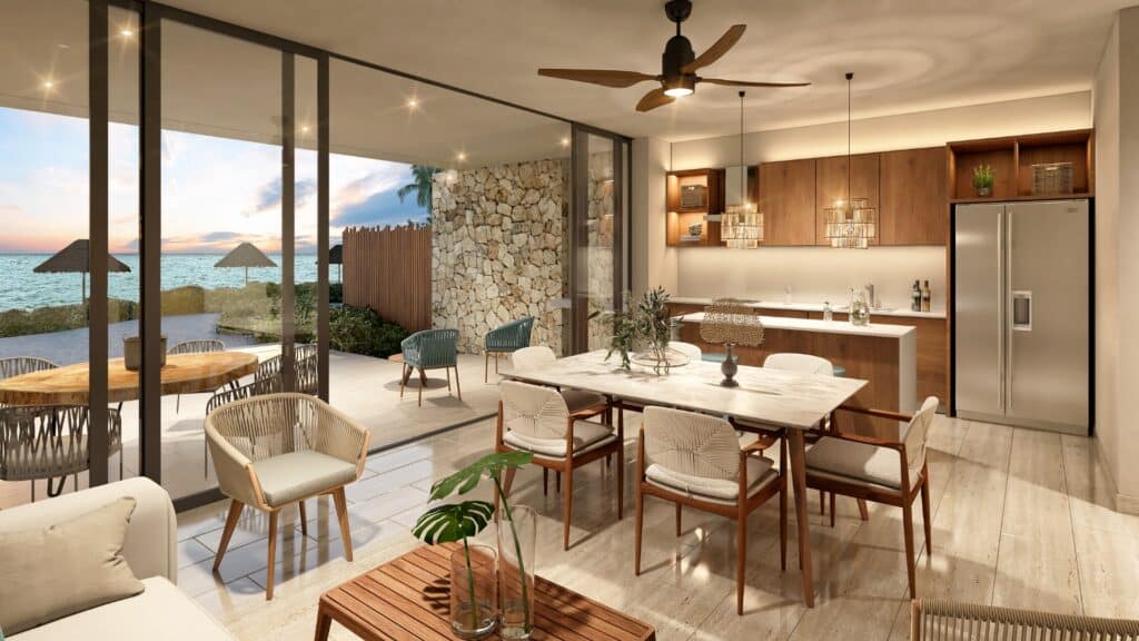 Interior of Duna Residences in Chuburna showing a modern, open-plan living and dining area with large sliding glass doors opening to a beachside view.