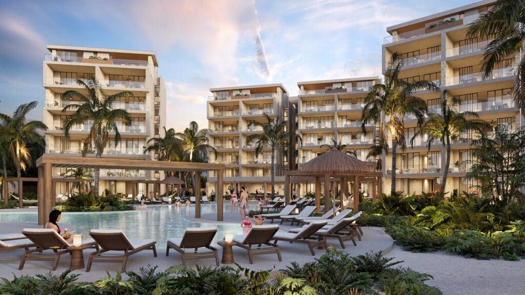 Duna Residences Beachfront in Chuburna features a modern multi-story building with a pool area surrounded by palm trees and lounge chairs.