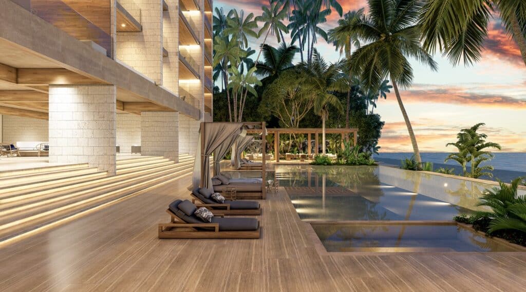A luxurious beachfront pool area at Madeira Vida De Mar in Chicxulub, featuring sun loungers, wooden cabanas, and tropical palm trees with a sunset sky.