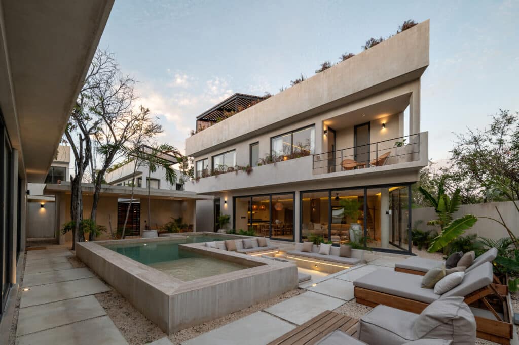 Twolum in Tulum features a modern exterior with a private pool, outdoor lounge area, and large glass doors opening into a stylish interior.