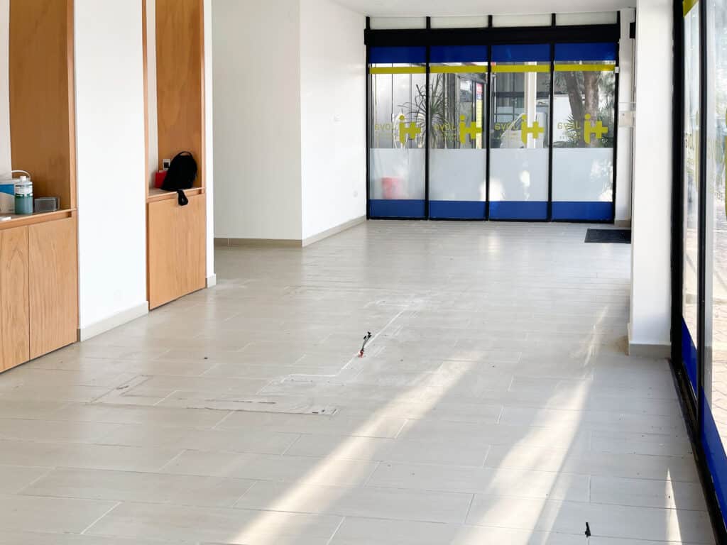 Interior view of Prime Highway Commercial Space in Puerto Aventuras, featuring a bright, open layout with large glass doors and light-colored flooring.