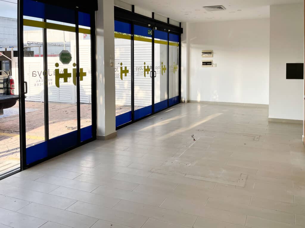 Interior view of a commercial space at Prime Highway Commercial Space in Puerto Aventuras, featuring large glass front doors and tiled flooring.