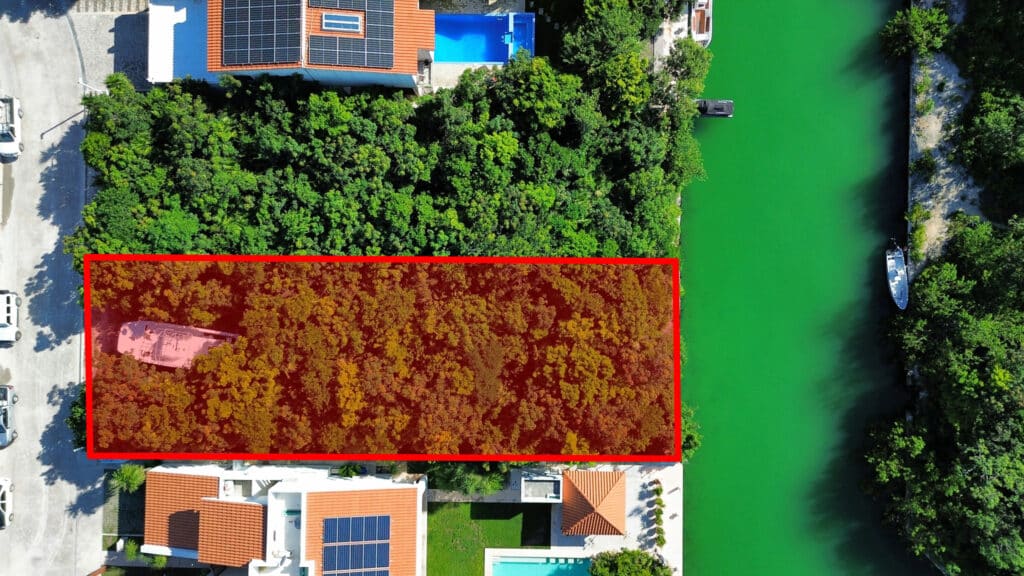 Aerial view of a land parcel in Phase 4 Canal Front, Puerto Aventuras, situated on Marina Front, with dense greenery and adjacent waterway.