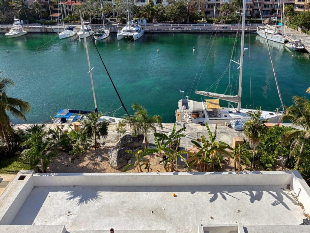 View of a marina with sailboats and lush greenery at Artesan Penthouse in Caleta Xel - Ha, Puerto Aventuras.