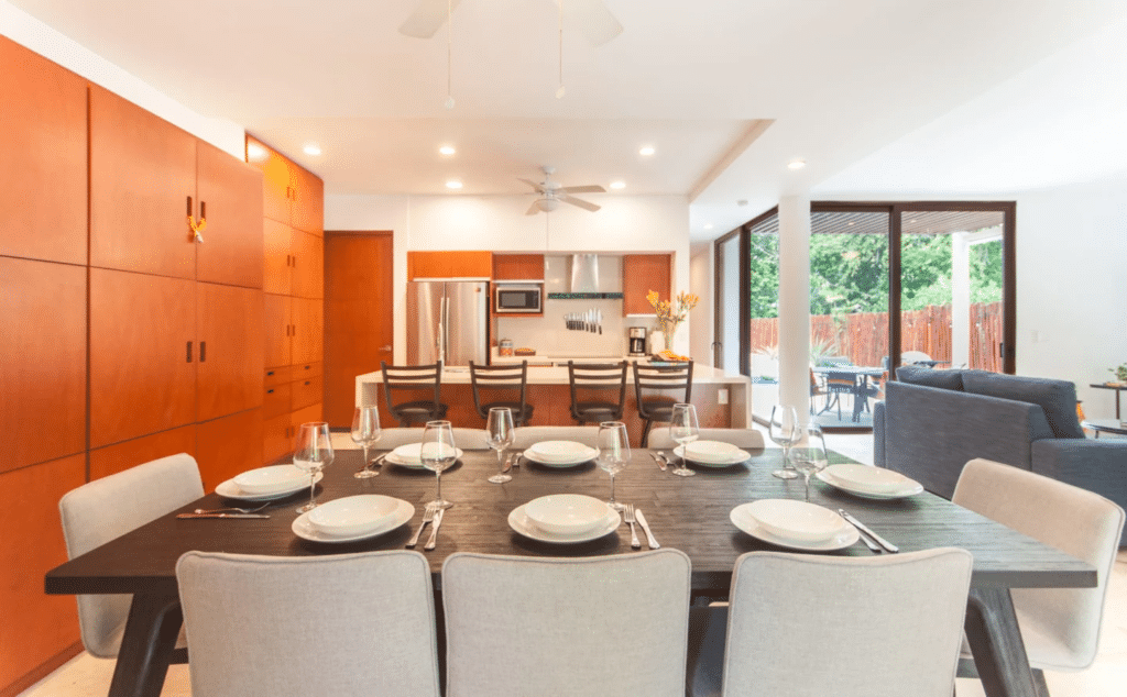 Open-plan kitchen and dining area with large sliding glass doors opening to outdoor space at Casa Bahamas in Tulum Country Club.