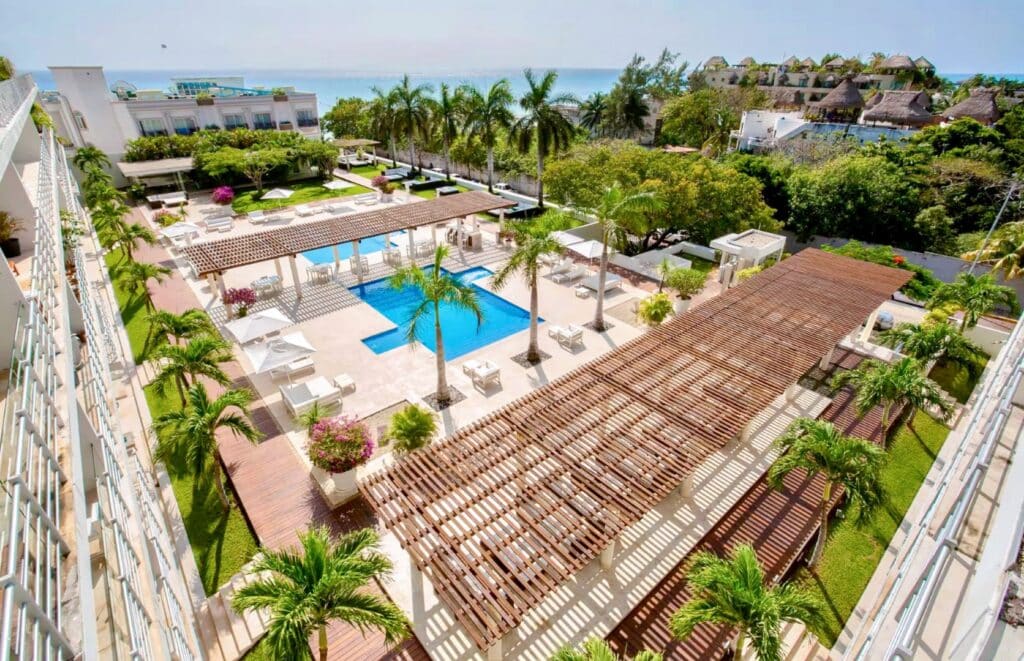 Aerial view of a swimming pool area with sun loungers and palm trees at Magia 202 F in Playa Centro, Playa del Carmen.