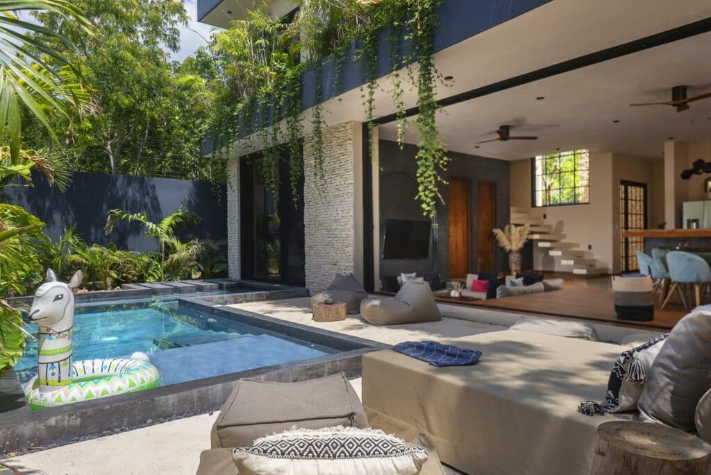 Open living area with a covered outdoor patio, pool, lush greenery, and modern interior design in Maison Siscolino, Tulum, Region 15.