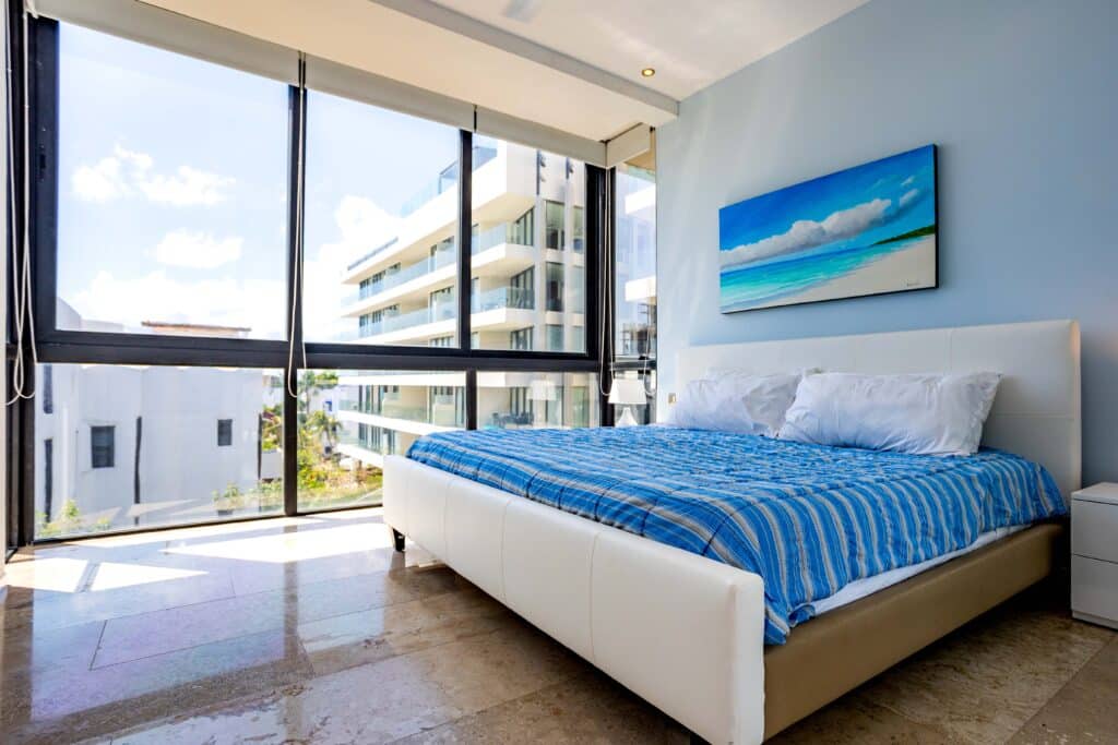 Bedroom with large windows and view of neighboring building in Menesse 301 apartment for rent, Coco Beach, Playa del Carmen at Menesse 301 2-Bedroom Condo.