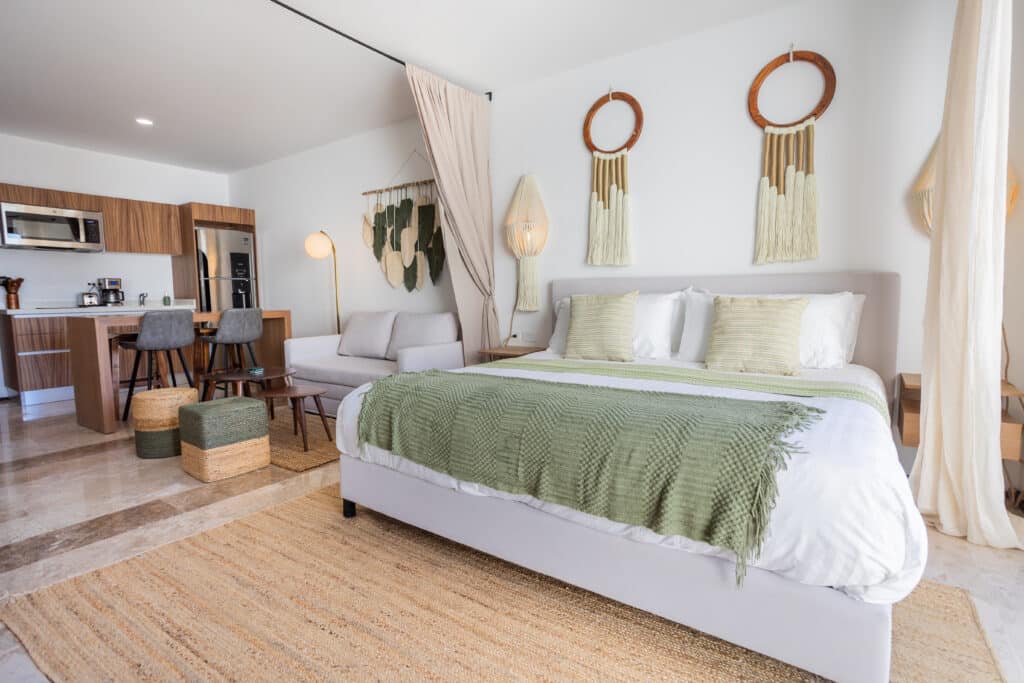 Interior view of a studio apartment with a bed, wall art, and a kitchen area at My Menesse 407 Studio in Playa Centro, Playa del Carmen.