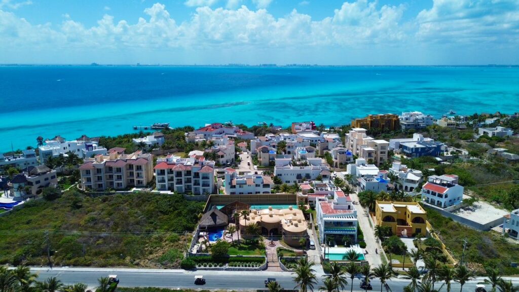 Aerial view of Casa de las Cúpulas Ocean View Villa with white and colorful buildings overlooking turquoise waters in Isla Mujeres.