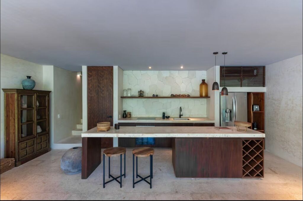 Modern kitchen with wooden cabinetry, white stone backsplash, stainless steel appliances, and pendant lighting in Sky Jungle 207.