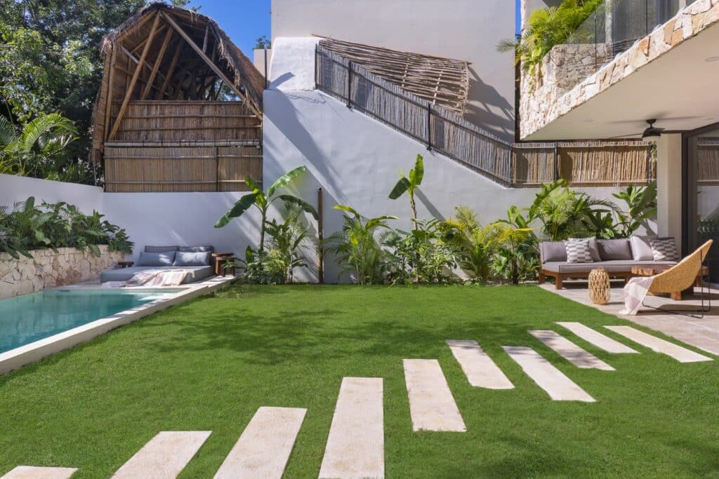 Outdoor pool area with lounge chairs, sofa, and lush greenery at Villa Eterea in Aldea Zama, Tulum.