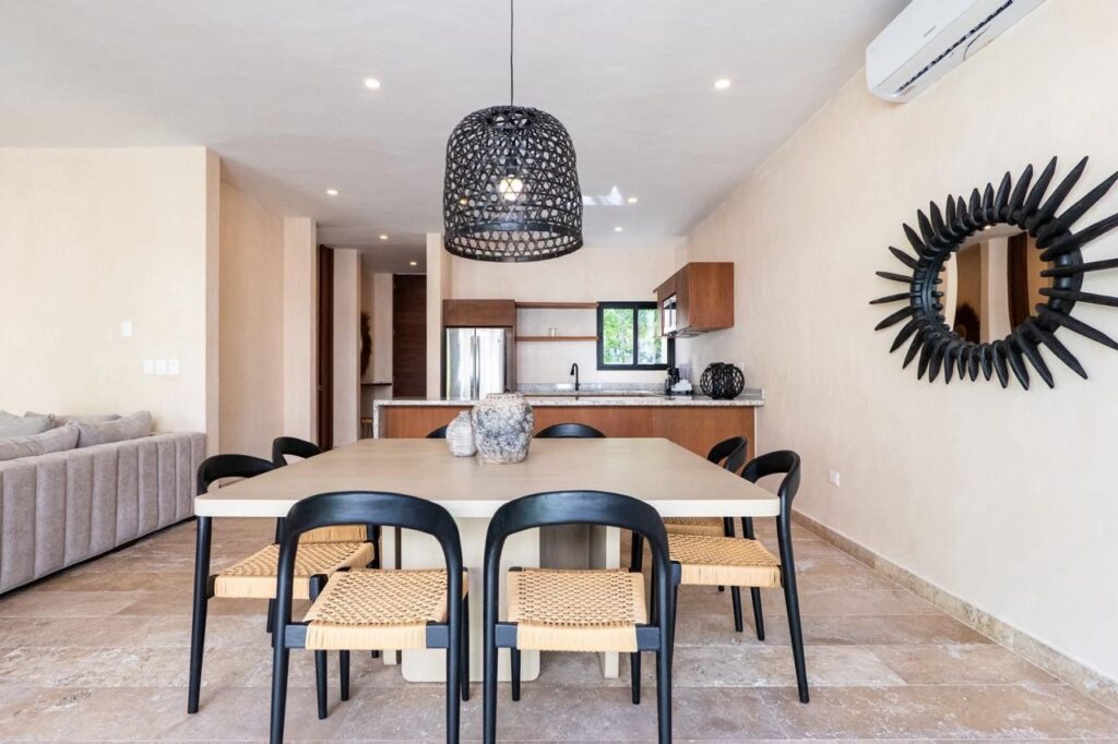 Open-plan living and dining area with modern kitchen and black decor accents in Villa Serenia, Kaybe Tulum.