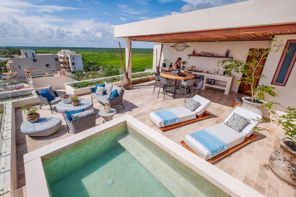 Rooftop terrace with seating area, loungers, small pool, and panoramic views of green landscape and blue sky at Kaoba in Tankah Bay, Tulum.