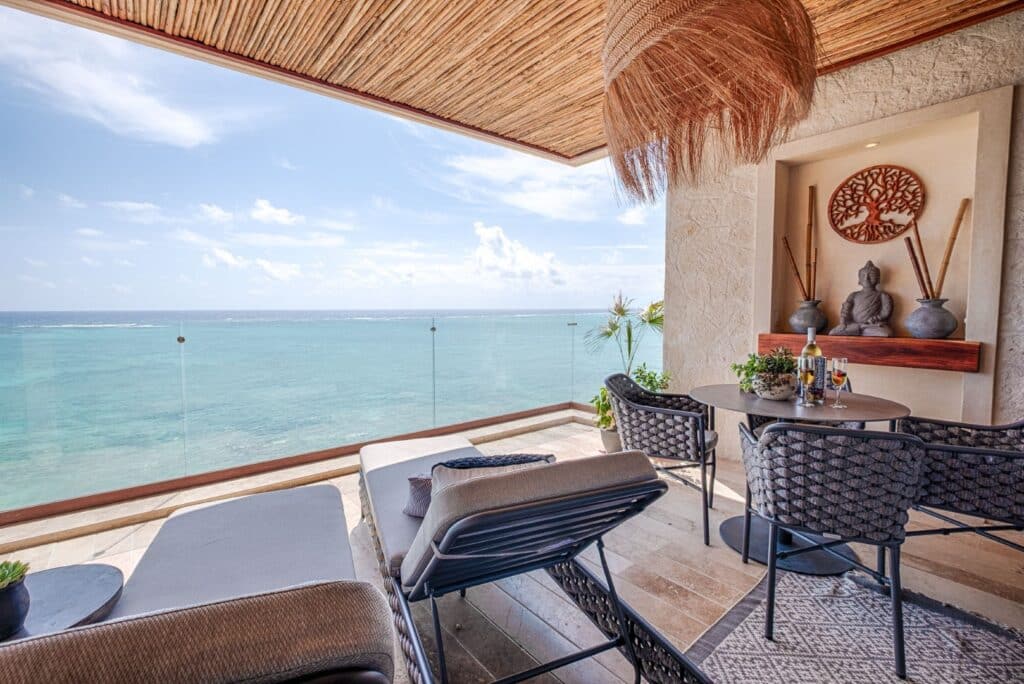 Balcony with ocean view featuring chairs, a table, and decorative art in Tulum, Mexico at Kaoba.