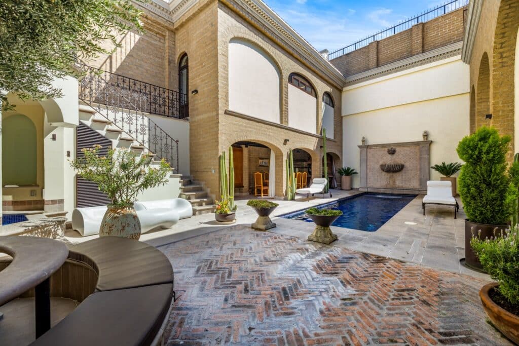 Beautiful courtyard with a swimming pool, seating area, and rustic brick and stone features at Casa 28 De Abril in San Miguel de Allende.