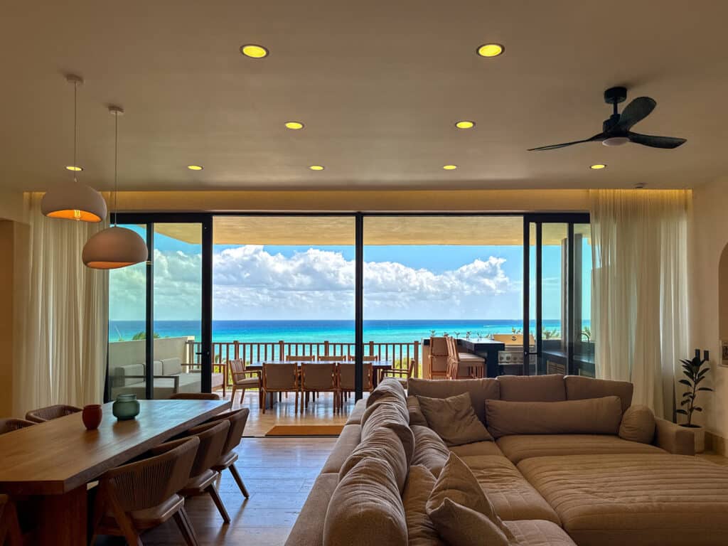 Living room with panoramic ocean view through large floor-to-ceiling windows in Playa del Carmen at Costa Beach.