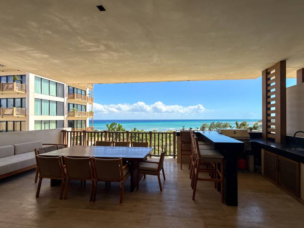 Indoor dining area with large windows offering ocean views, wooden furniture, and a bar counter in a beachfront property in Playa del Carmen at Costa Beach.