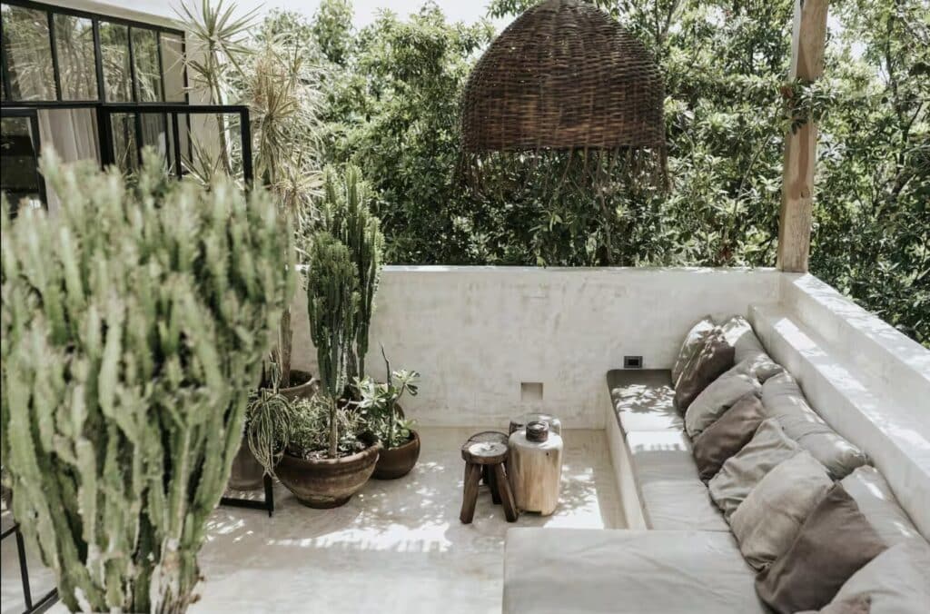 Outdoor seating area with cactus plants, woven pendant light, and lush green background in Tulum at Canopia.