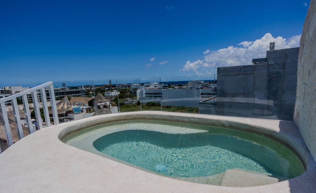 View from Luna residences rooftop with a hot tub overlooking Playa del Carmen and the Caribbean Sea on a clear day.
