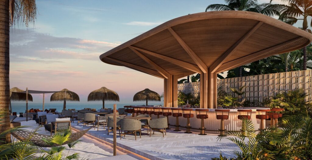 Beachside bar with thatched umbrellas, lounge chairs, and lush tropical plants against a sunset sky at Viceroy Residences in Playa del Carmen.